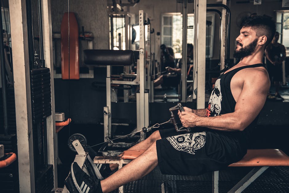 Muscular man focused on seated cable row training in an indoor gym setting