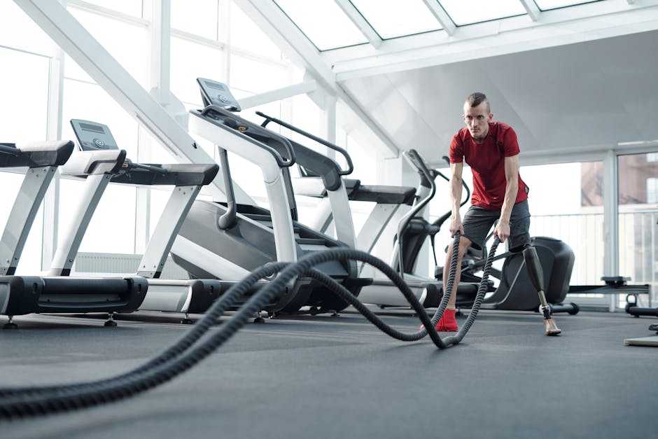 Young man with prosthetic leg working out in a modern gym with battle ropes