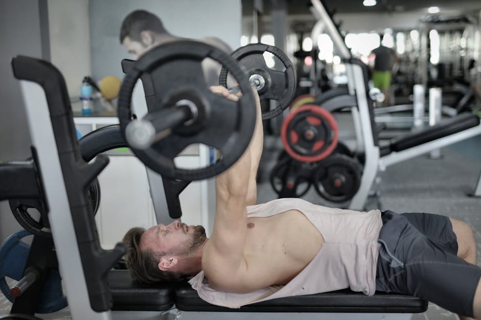 Side view of strong young sportsman pressing heavy barbell doing chest exercise in modern gym