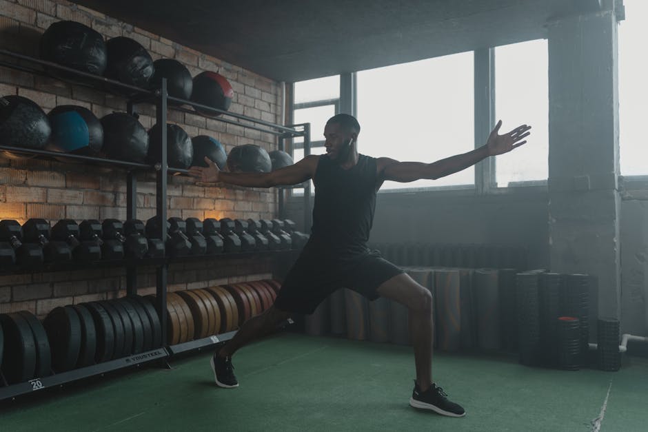A muscular black man stretching in a modern gym with fitness equipment