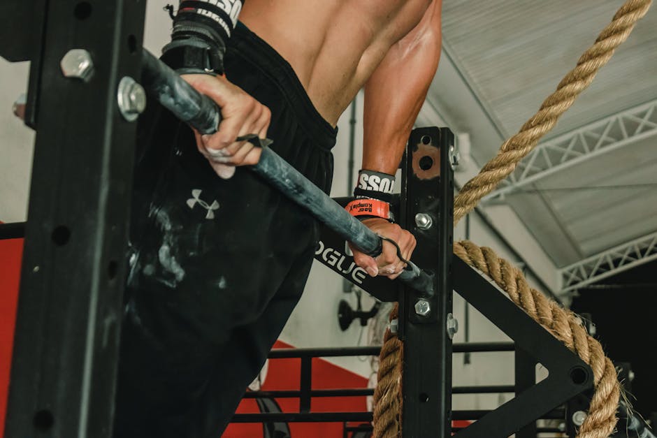 A muscular man performing a pull-up exercise indoors, showcasing strength and fitness