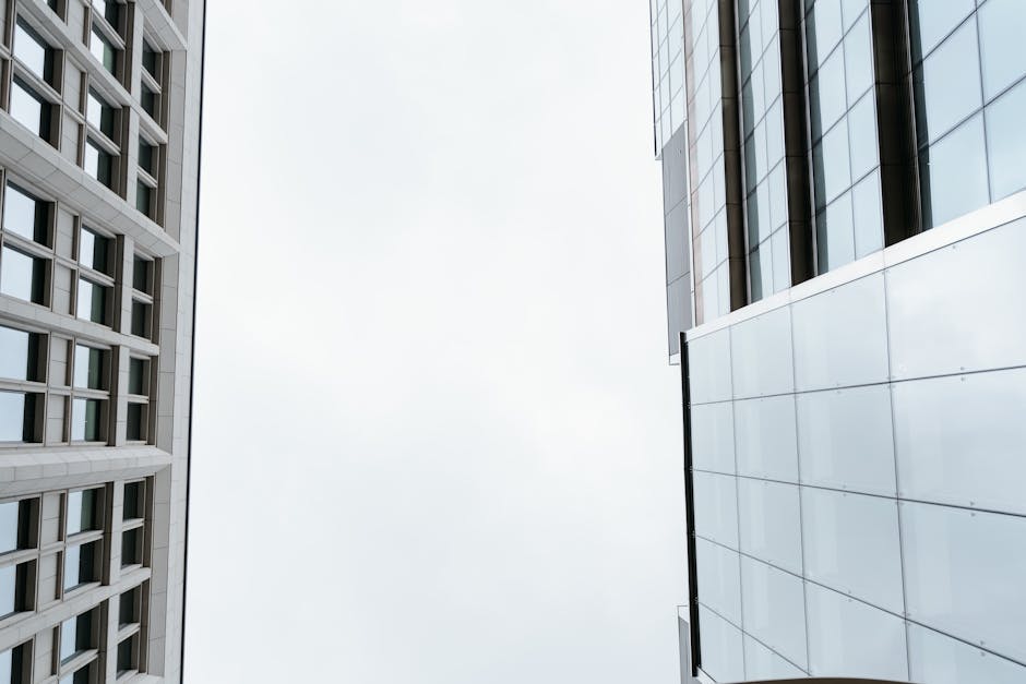 Low-angle view of modern skyscraper facades against a cloudy sky