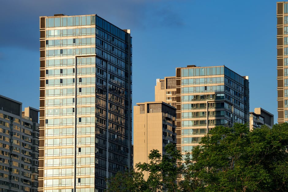 Contemporary high-rise buildings with glass facades at sunset, surrounded by nature