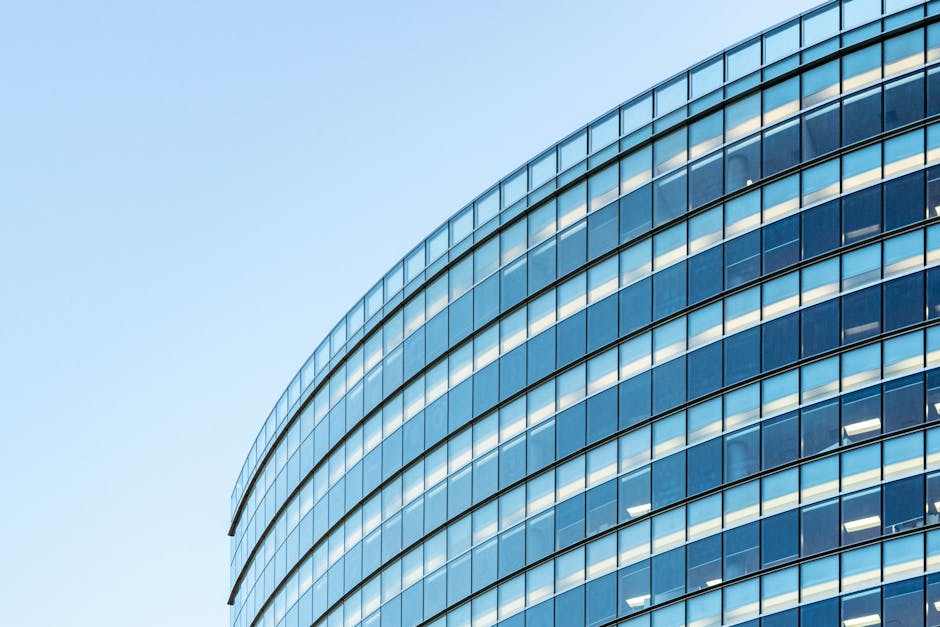 Low angle view of a modern glass office building against a clear blue sky
